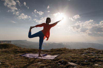 Woman doing yoga, natarajasana asana - outdoor dance pose at sunset in the mountains. a yogi on a