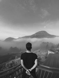 Rear view of man looking at mountains against sky