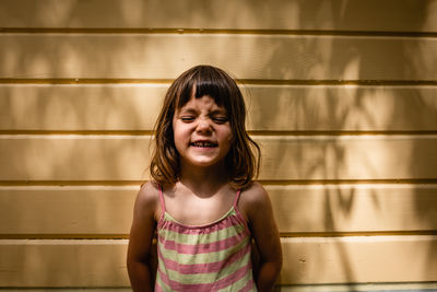 Portrait of laughing little child on a sunny day against yellow wall