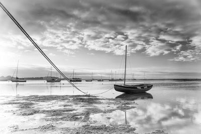 Sailboats moored on sea against sky