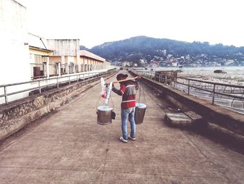 Rear view of women standing on bridge in city