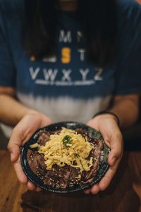 Midsection of man holding food in plate at table