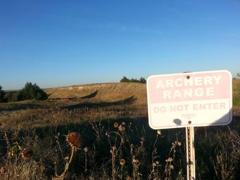 Information sign on landscape against clear blue sky