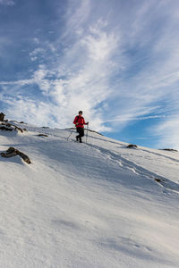 Man hiking on snowcapped mountain against sky