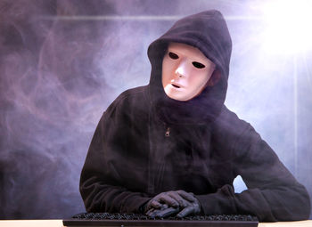 Computer hacker wearing mask and black hood