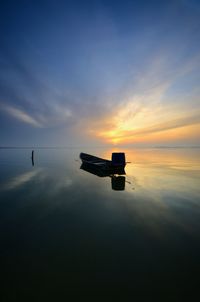 Silhouette boat in lake against sky during sunset