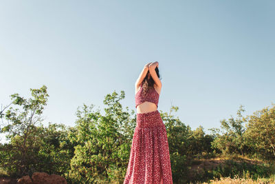 Woman standing by plants against sky