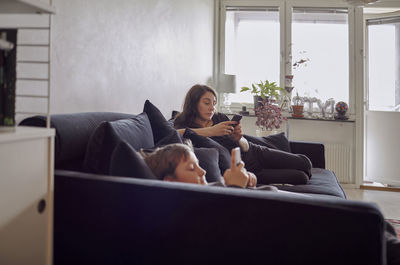 Mother and son lying on sofa and using cell phones