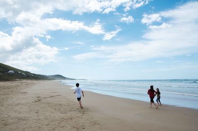 People walking on beach against sky