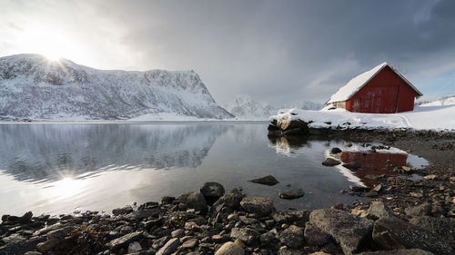 Scenic view of lake by mountain against sky during winter