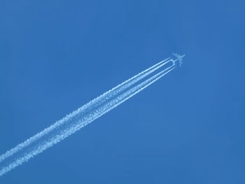 Low angle view of vapor trail against blue sky