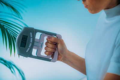 Close-up of man holding mobile phone against wall