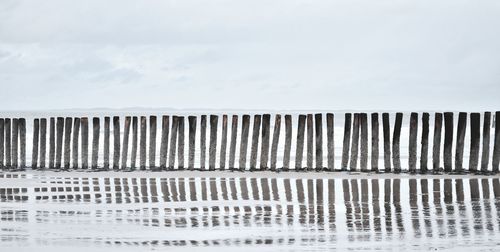 Reflection in the water of wooden breakwaters in the sea.