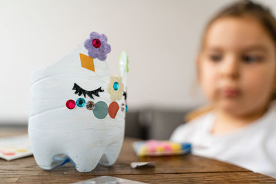 Close-up of boy with piggy bank on table