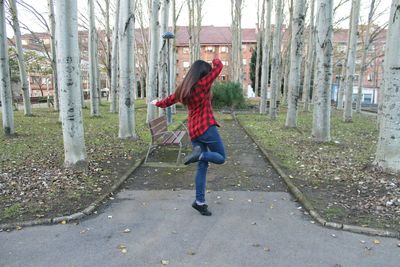 Side view of young woman on bare tree