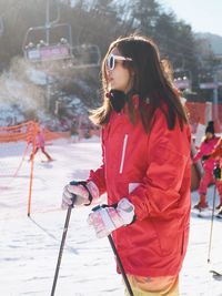 Side view of young woman skiing on snow covered field