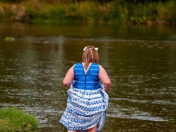 Rear view of woman standing against river