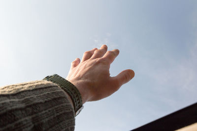 Close-up of hand against sky