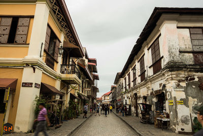 People walking on road along buildings