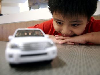 Smiling boy looking at toy car on table