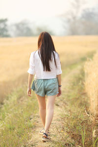 Rear view of woman walking on field