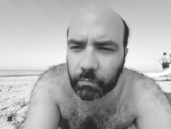 Portrait of shirtless man in sea against sky