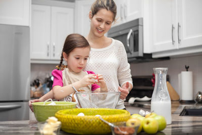 Cute girl with mother preparing food in kitchen
