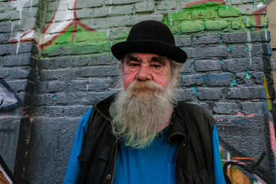 Portrait of man while standing against wall