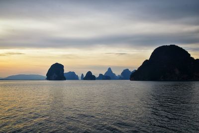 Rocks in sea against sky during sunset