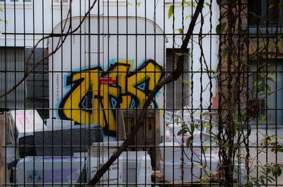 Graffiti on chainlink fence against sky in city