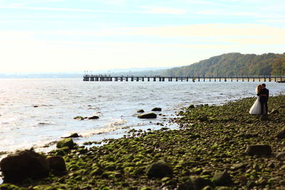 Bride and bridegroom standing on shore at beach