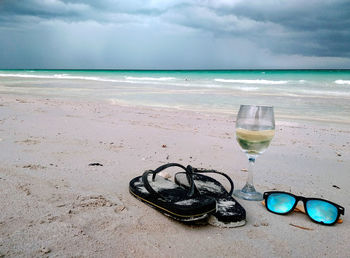 Sunglasses on sea shore against sky