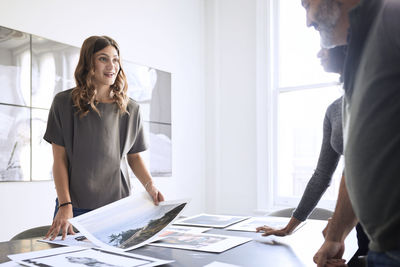 Business people examining photograph printouts in board room