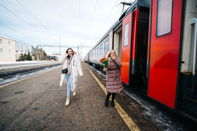 Girls with flowers on the station platform meet the arriving train