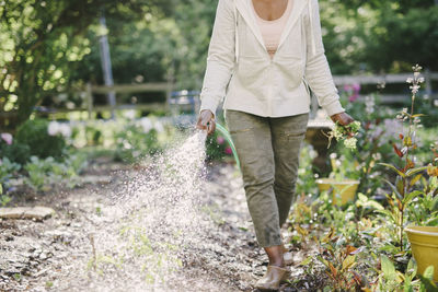 Low section of woman watering plants in garden