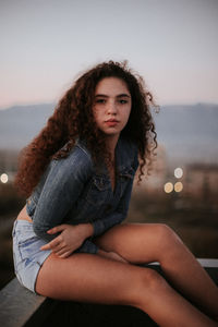 Portrait of young woman sitting outdoors during sunset