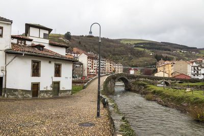 Bridge over river amidst buildings against sky