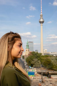 Smiling young woman looking away against berliner fernsehturm
