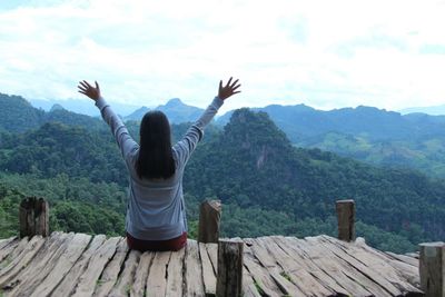 Rear view of woman sitting on landscape against sky