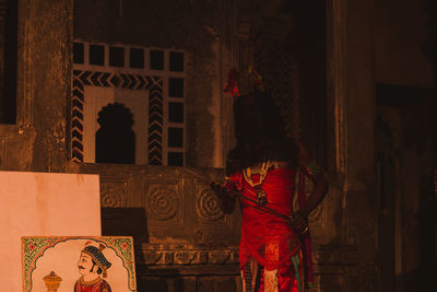 Front view of man standing against red building