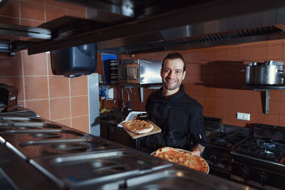 Pizza making process. male chef making authentic pizza in the pizzeria kitchen.