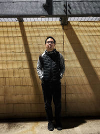 Portrait of young man standing against wall