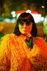 Portrait of woman wearing sunglasses and warm clothing at night