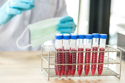 Midsection of doctor by blood in test tubes on table at hospital