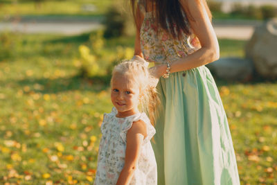 Daughter with mother on grass in park