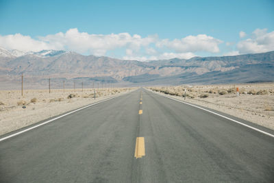 Road by mountains against sky