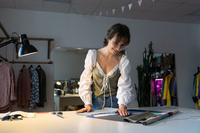 Young designer woman dressmaker work on new clothes collection in studio workshop. small business.