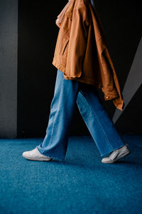 Low section of woman standing against blue wall