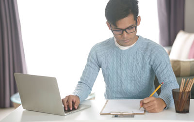 Man using mobile phone while sitting on table