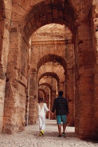 Rear view of couple walking in archway